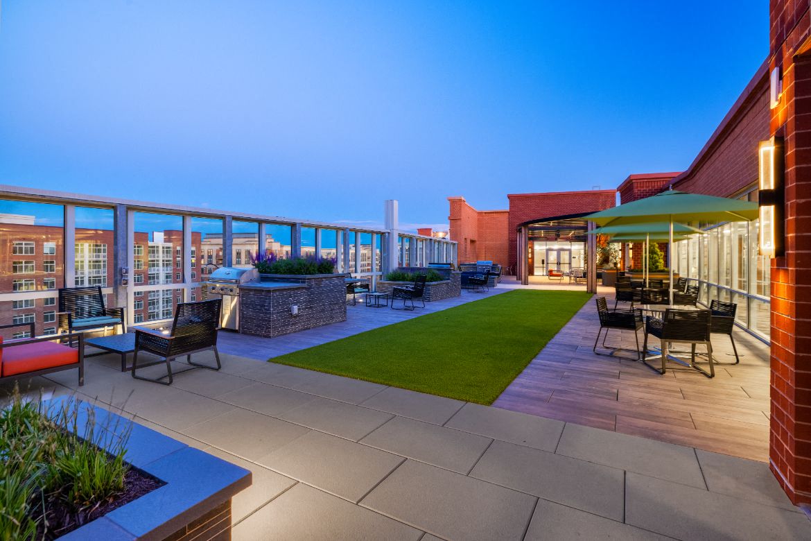 a patio with tables and chairs and a lawn