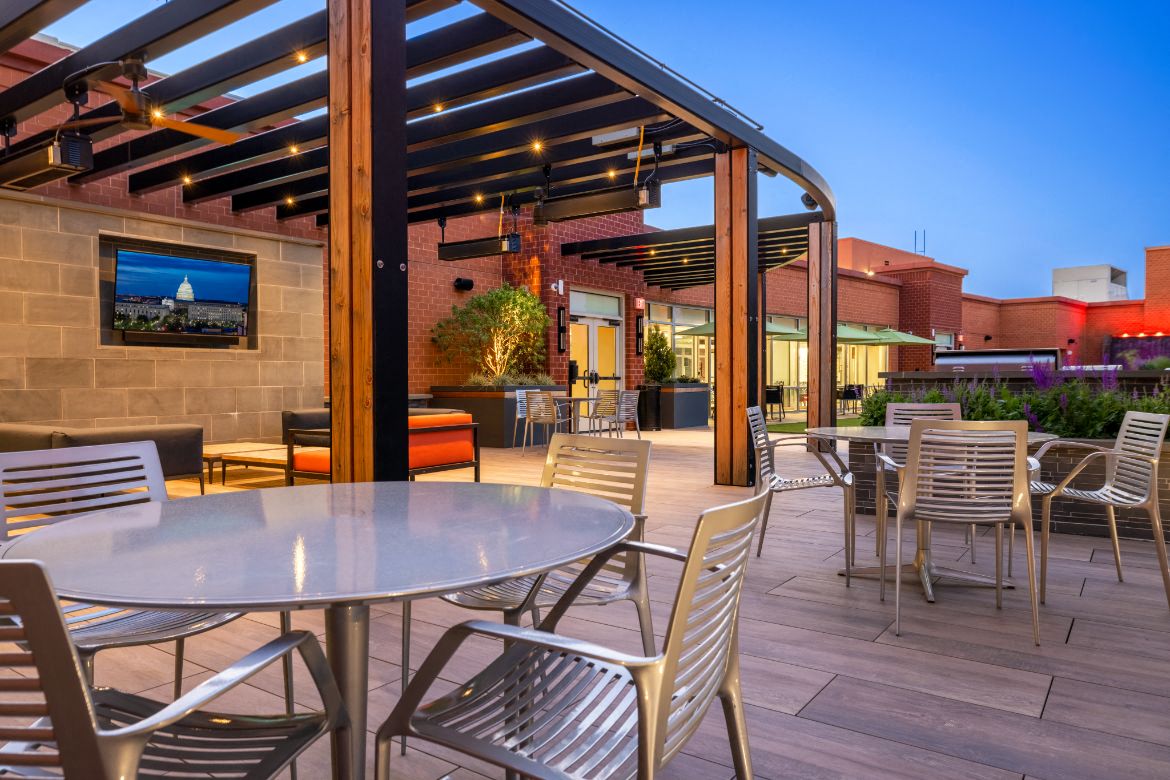 a patio with tables and chairs and a tv on the wall