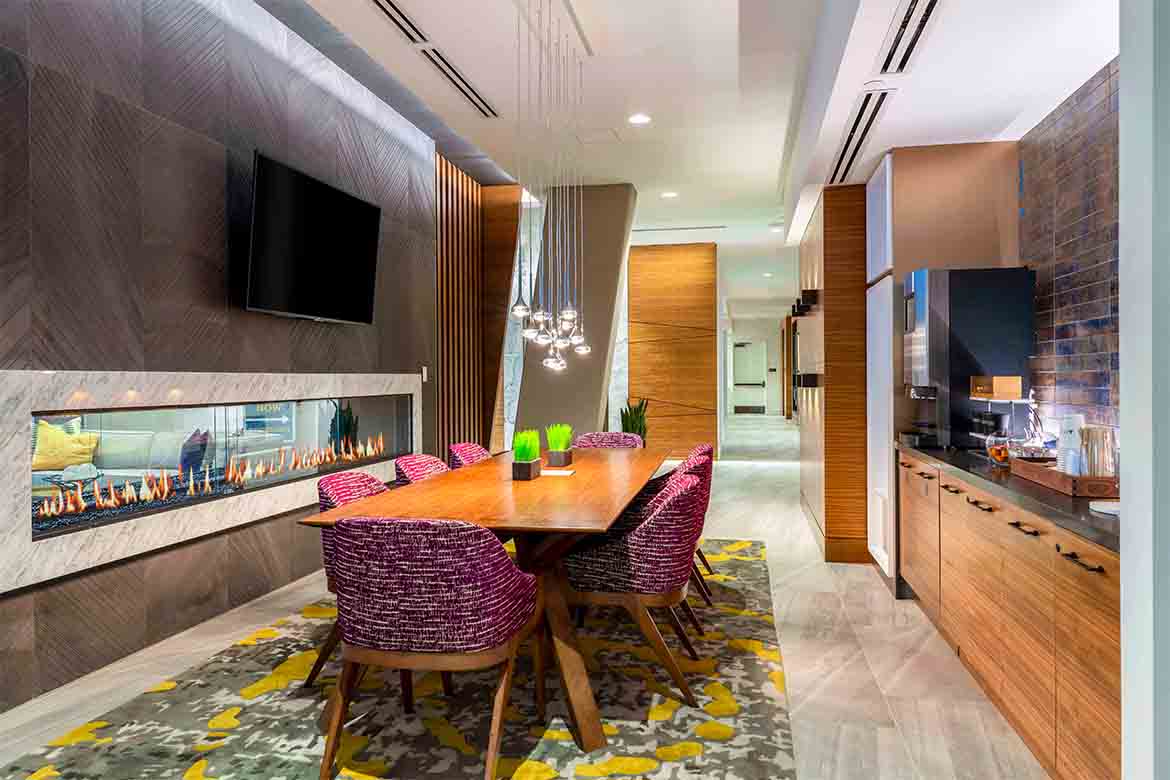 a dining room with a wooden table and chairs in front of a fireplace