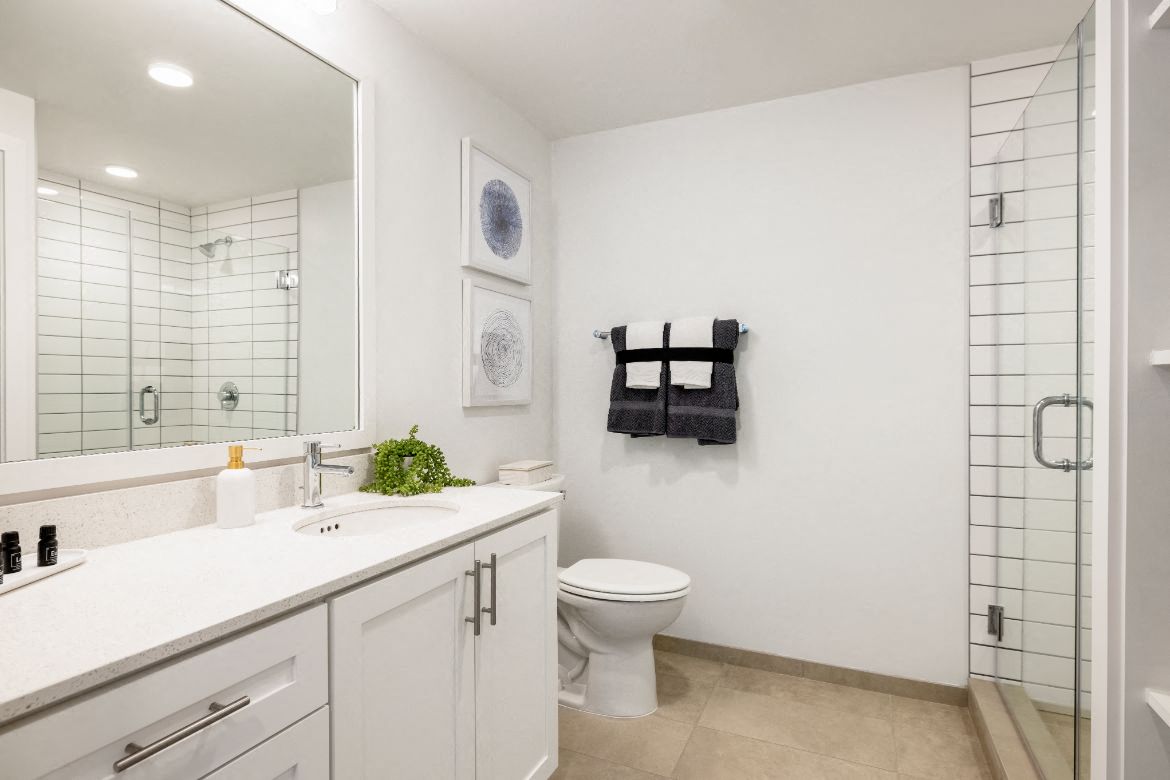 a white bathroom with a large mirror and a toilet