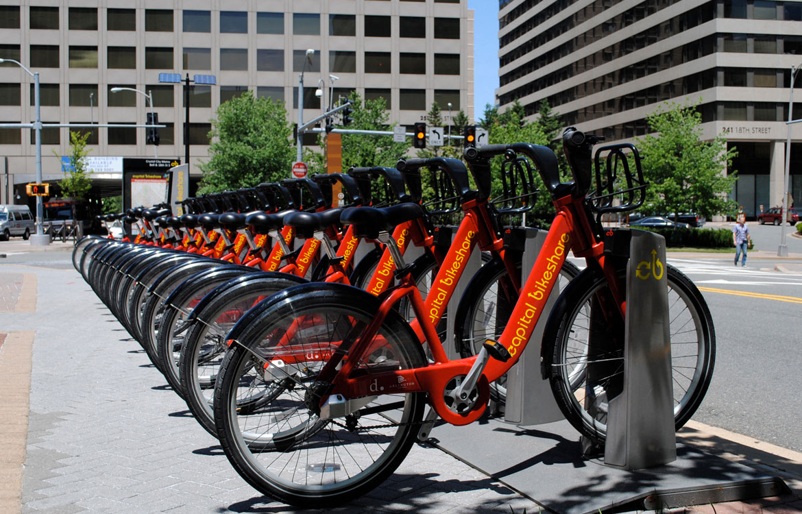 a row of orange bikes parked on the side of a street
