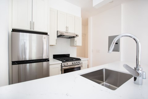 A modern kitchen with a stainless steel refrigerator and a stainless steel sink.