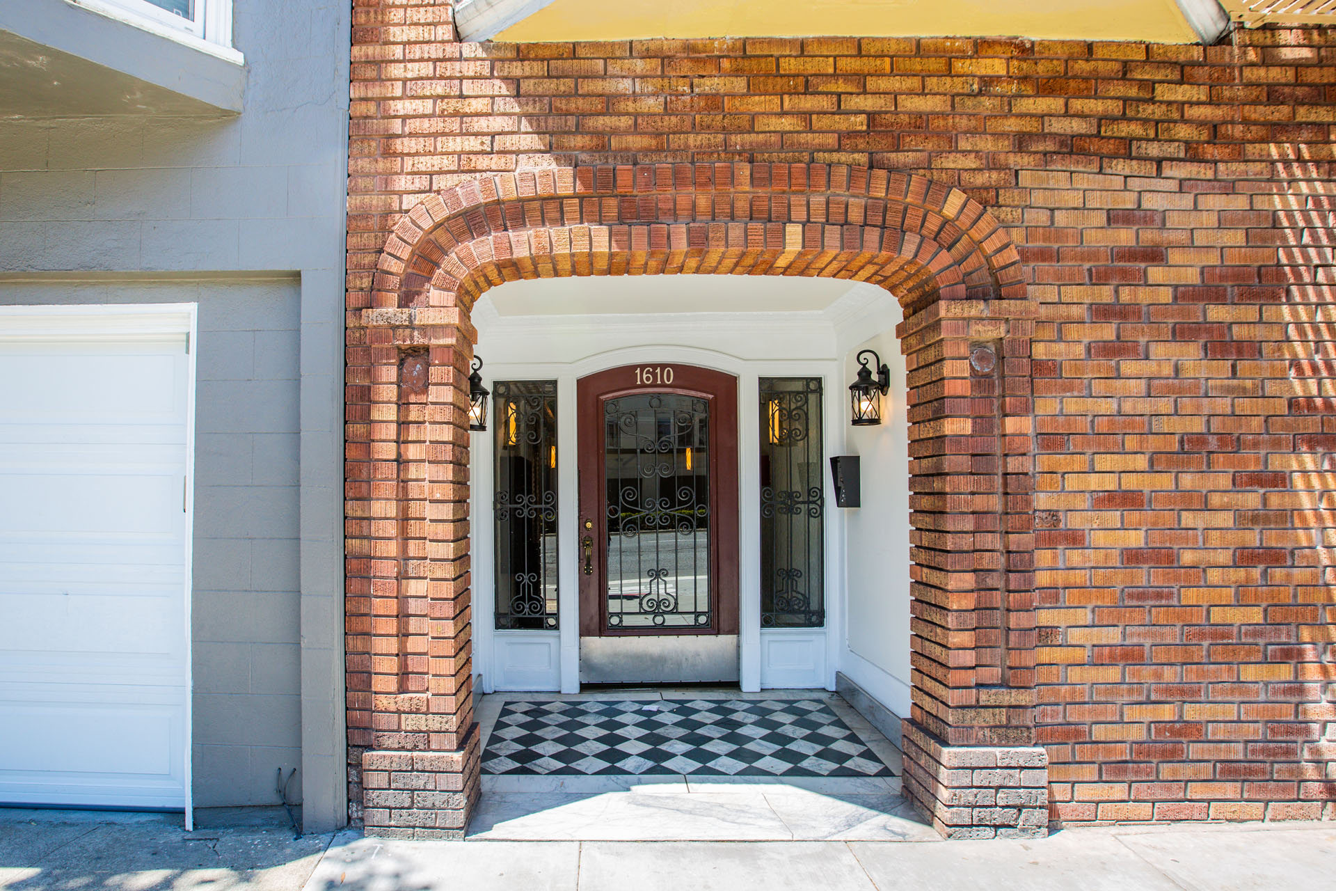 A red brick house with a white door and a black and white checkered floor.