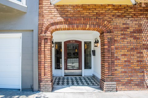 A red brick house with a white door and a black and white checkered floor.