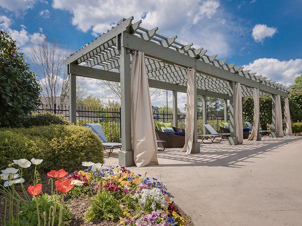 a pergola with chairs and curtains on a sidewalk