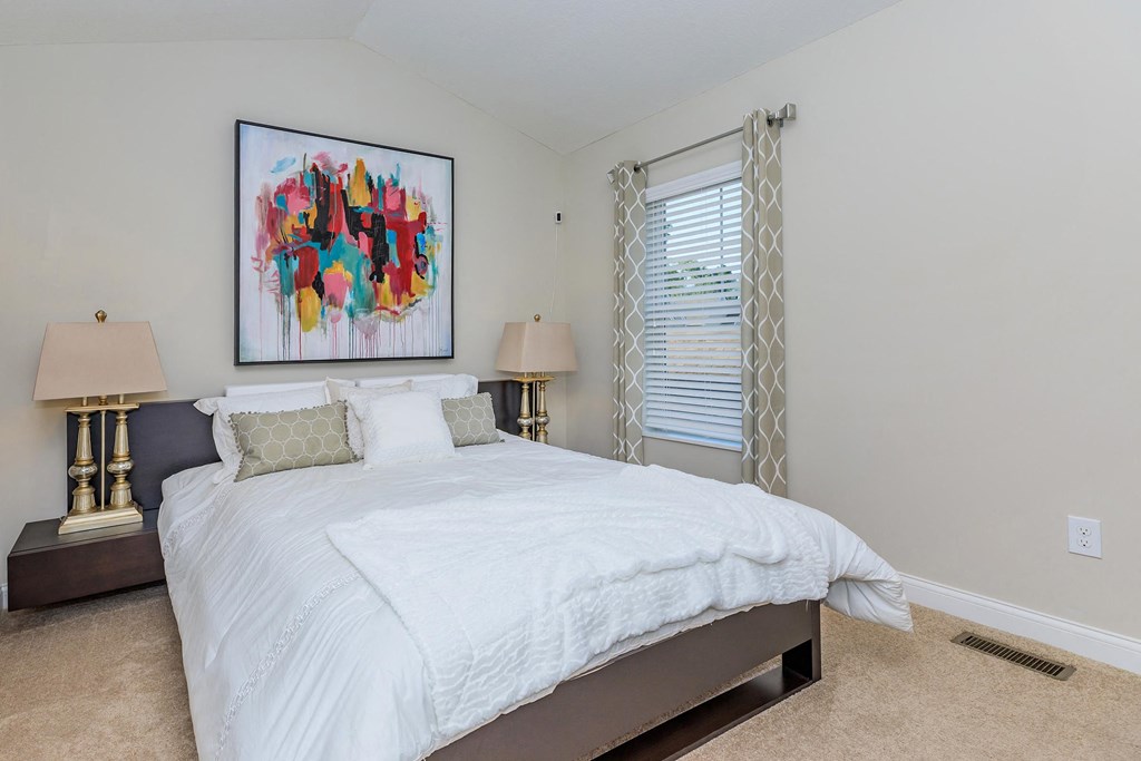 a bedroom with a bed and a painting on the wall