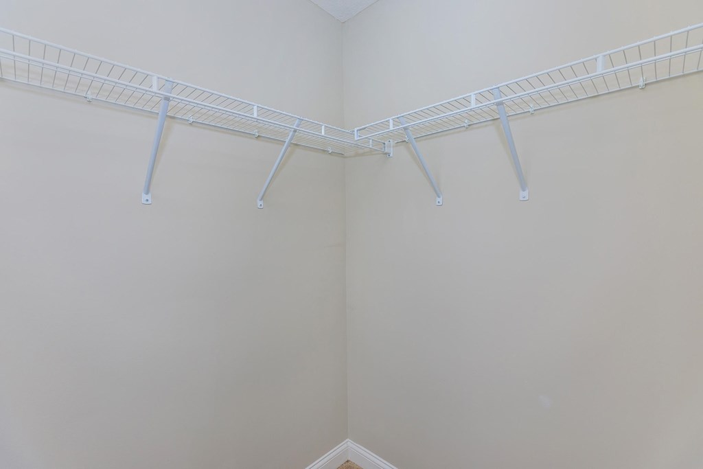 the walk in closet in the master bedroom of a home with white walls