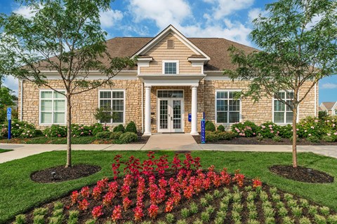 the front of a brick house with trees and flowers