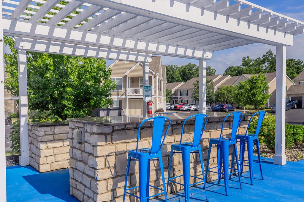 a bar with blue bar stools under a white pergola