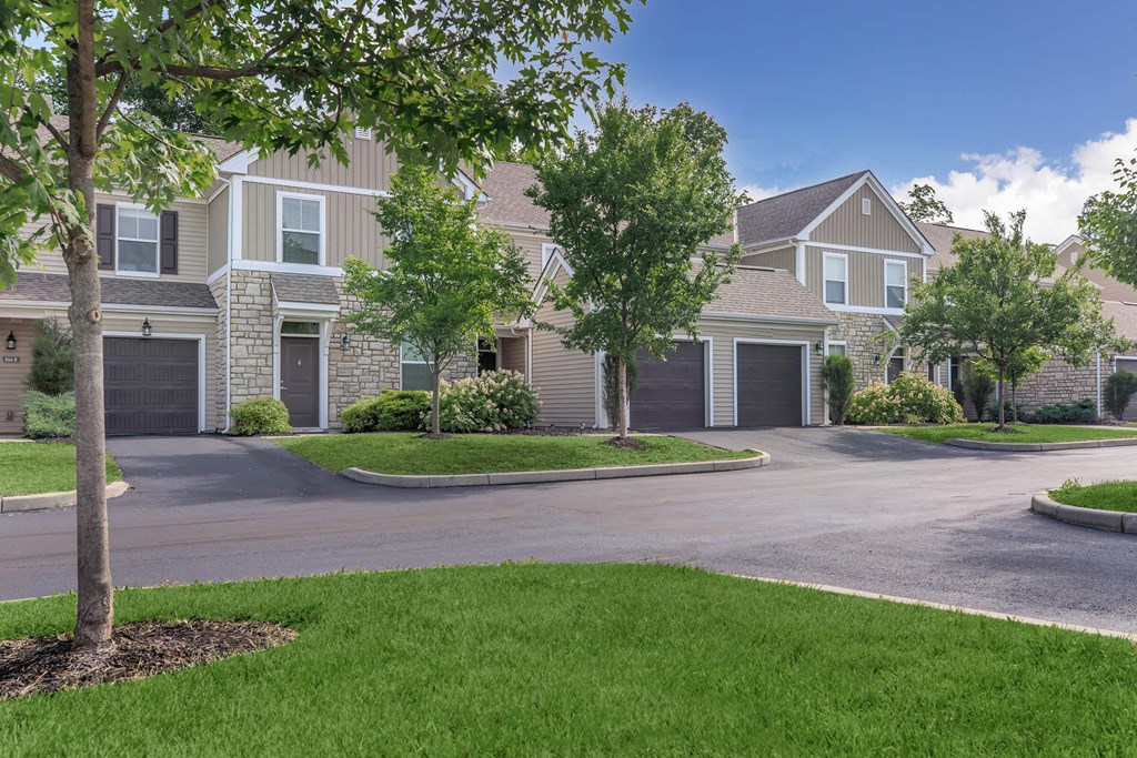 a house with a driveway and trees in front of it