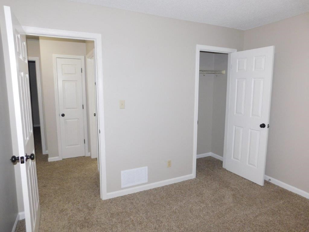 an empty bedroom with two doors and a closet