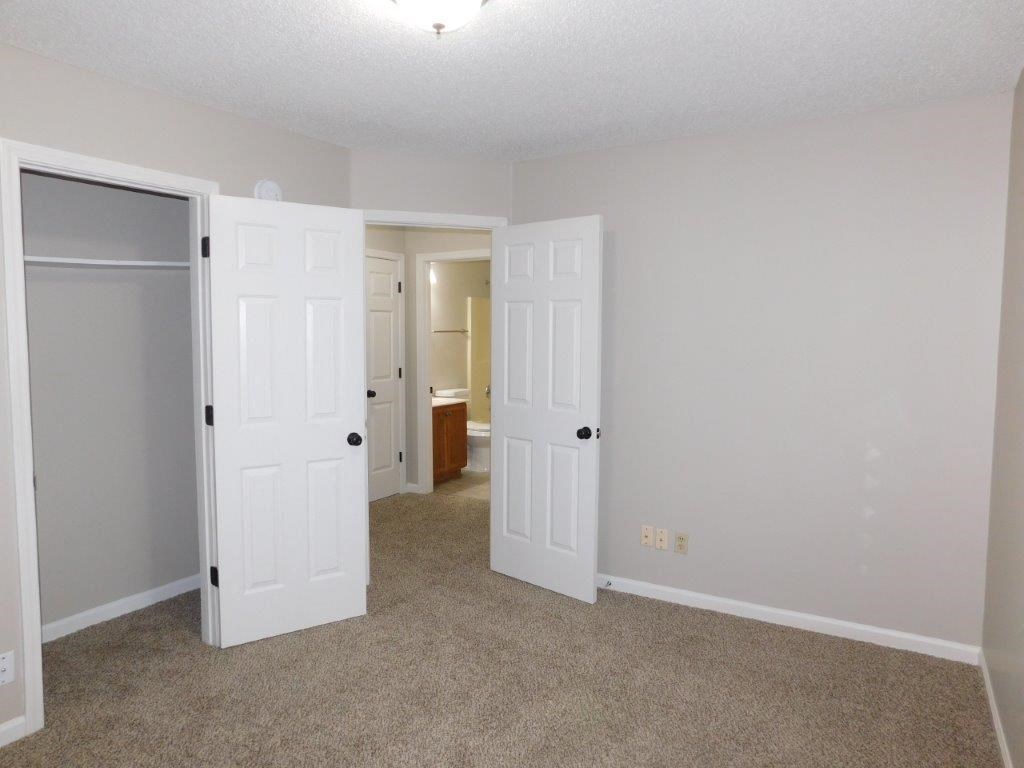 an empty living room with doors open to a bathroom
