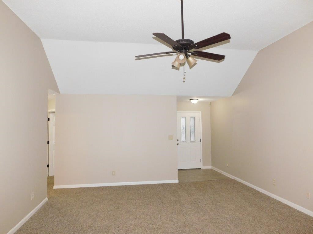 an empty living room with a ceiling fan