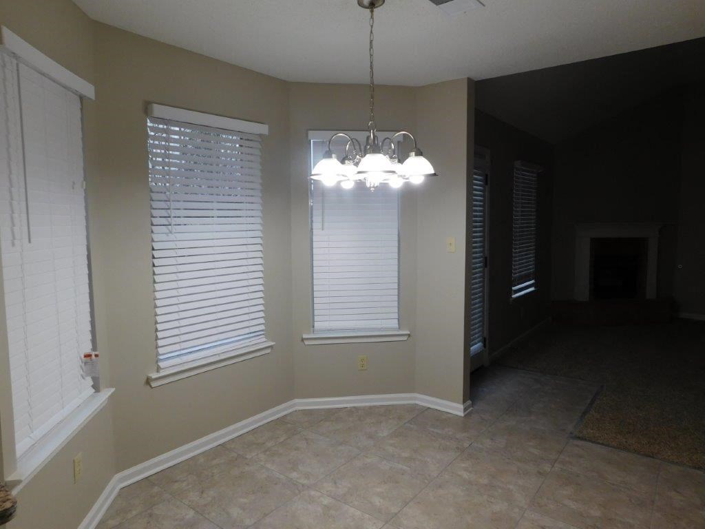 an empty dining room with a large window and a chandelier