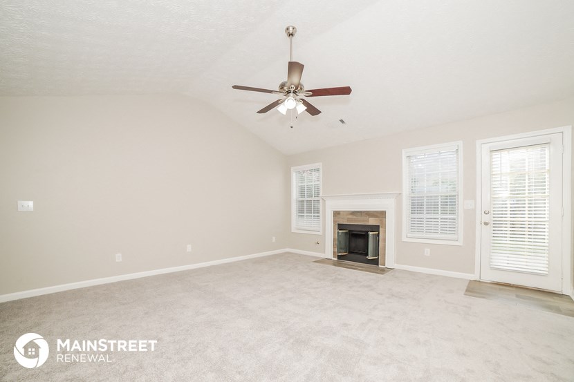 the spacious living room with fireplace and ceiling fan