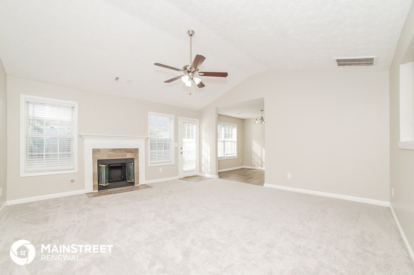 a living room with a fireplace and a ceiling fan
