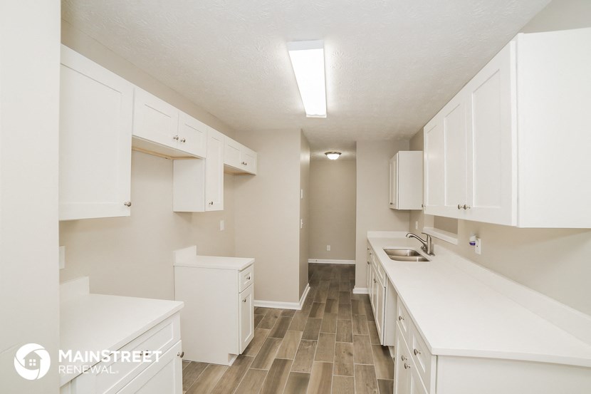 a white kitchen with white cabinets and white counter tops and wood floors