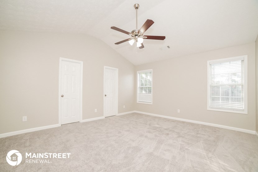 the spacious living room with ceiling fan and carpeting