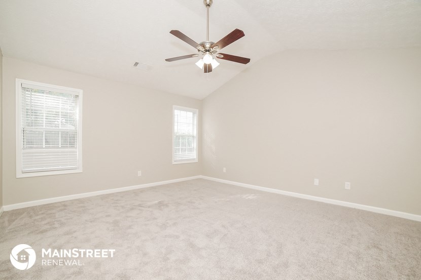the spacious living room with carpeting and a ceiling fan