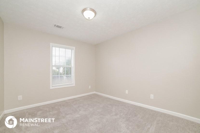 the spacious living room with carpeting and a window