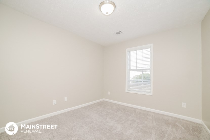 the upstairs bedroom with carpeted flooring and a window