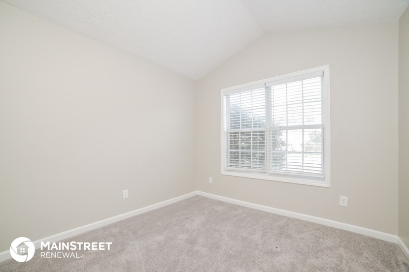the upstairs bedroom with carpeting and a large window