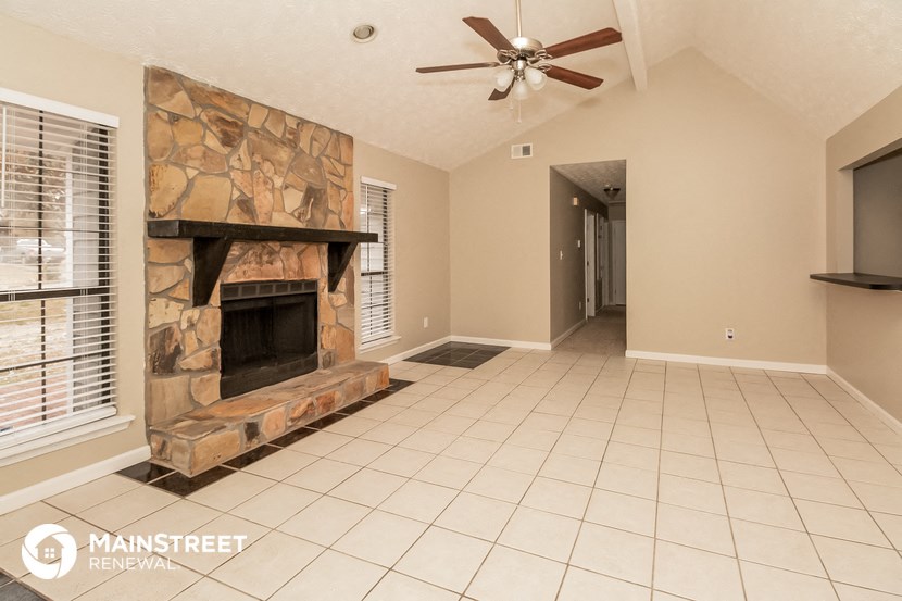 the living room has a large fireplace and a tiled floor
