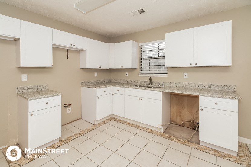 an empty kitchen with white cabinets and counters and a sink