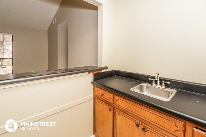 a bathroom with a sink and a mirror and wooden cabinets