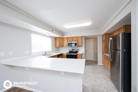 a kitchen with white countertops and wooden cabinets and stainless steel appliances