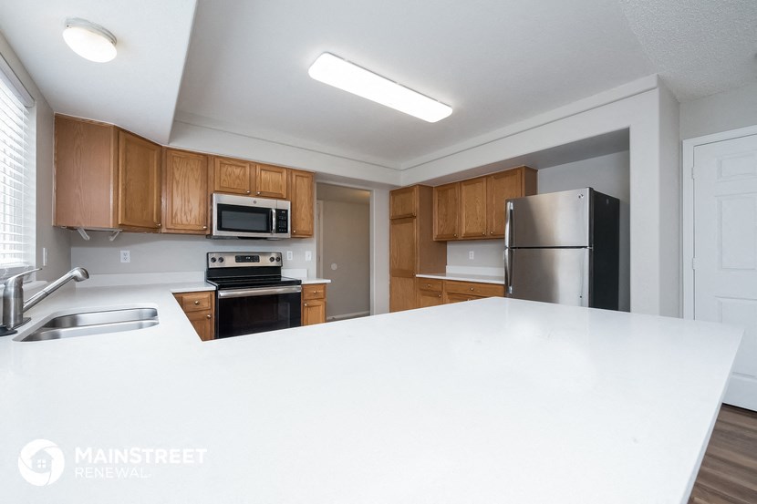 a kitchen with a white counter top and wooden cabinets