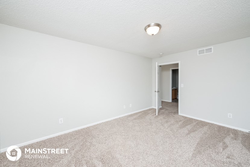 the spacious living room with carpeting and white walls