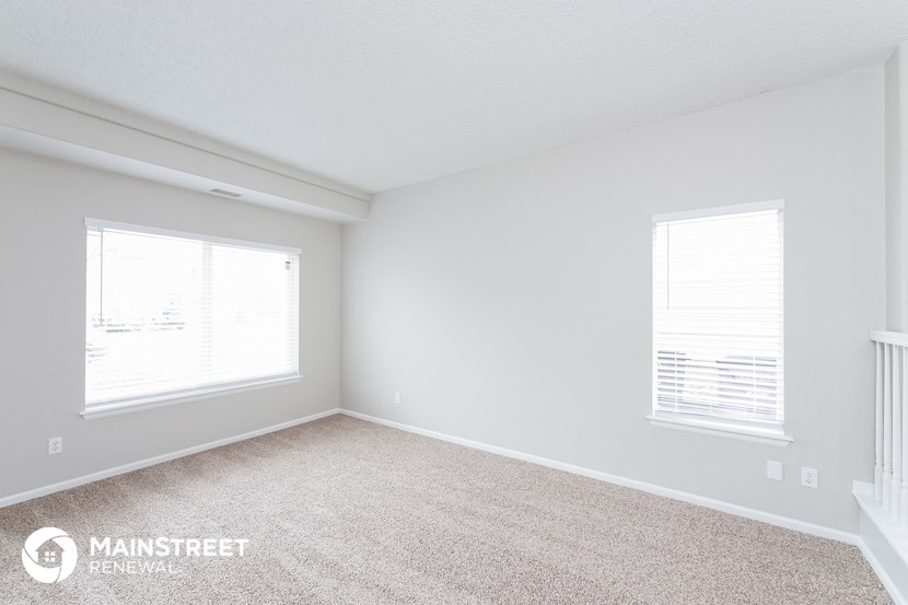 a bedroom with two windows and a carpeted floor