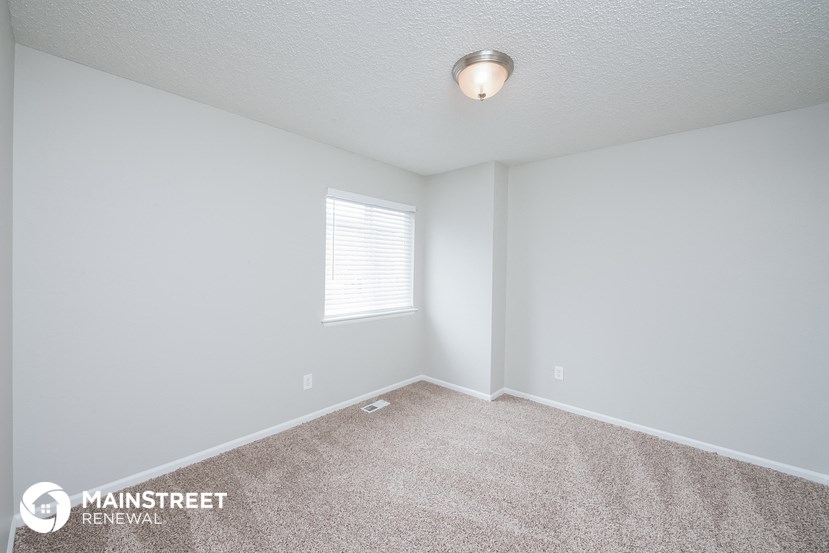 the spacious living room with carpeting and a window
