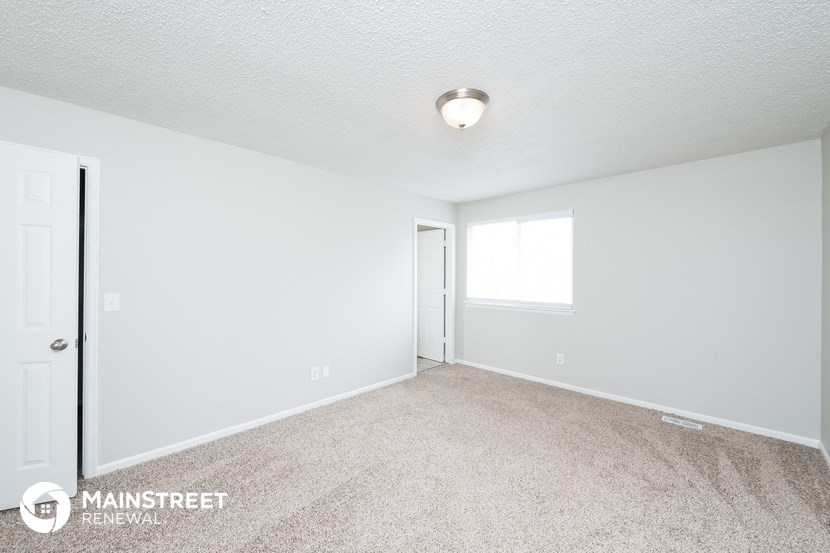 the spacious living room with carpeting and a door to the bedroom