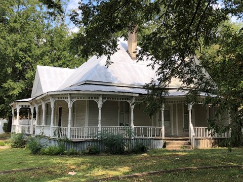A white house with a porch and a chimney.