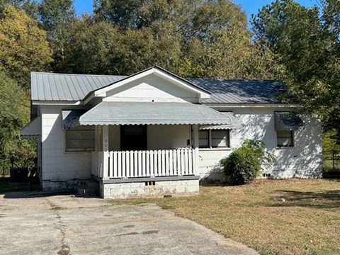 A white house with a porch and a grey roof.