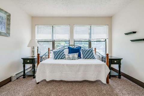 a bedroom with a bed and three windows