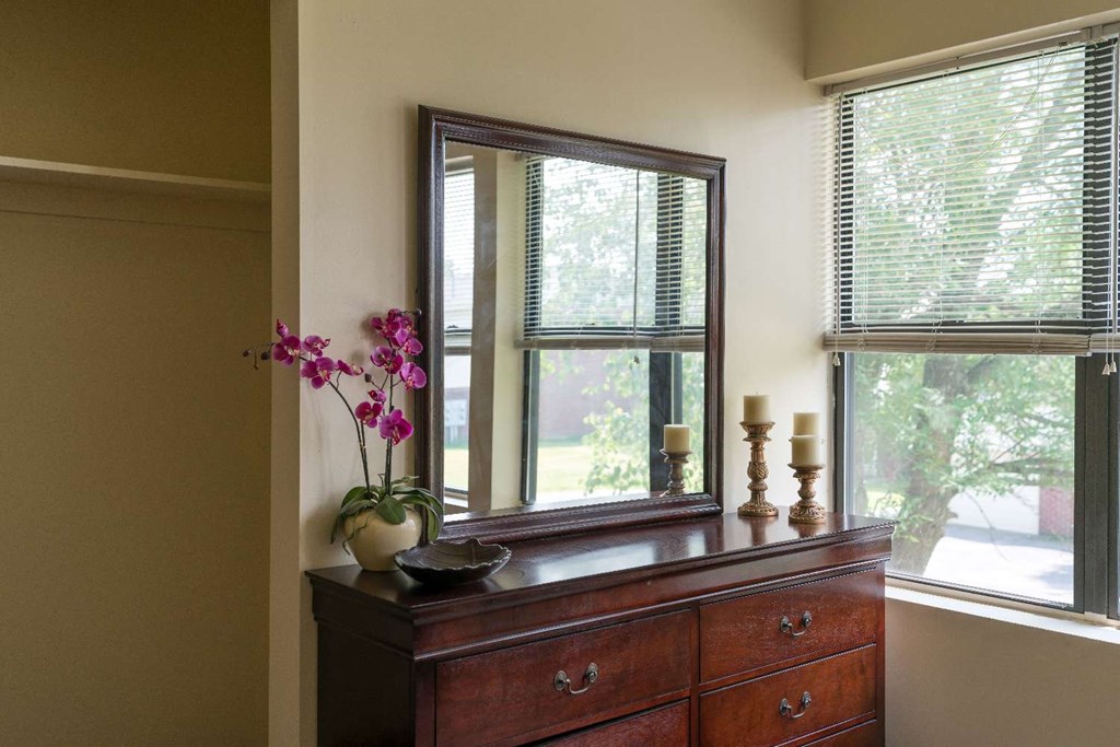 a mirror on top of a dresser next to a window