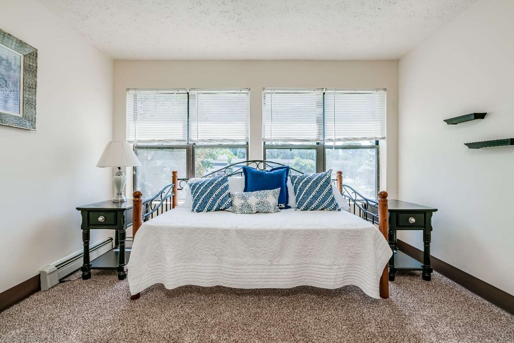 a bedroom with a bed and three windows