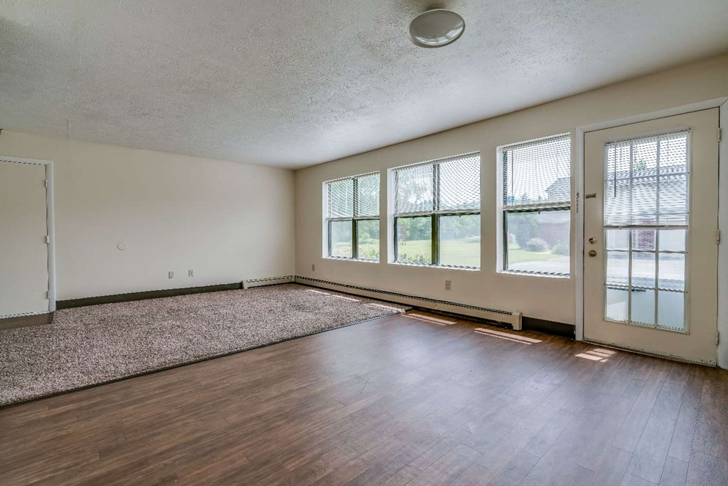 the living room of an empty house with wood floors and windows