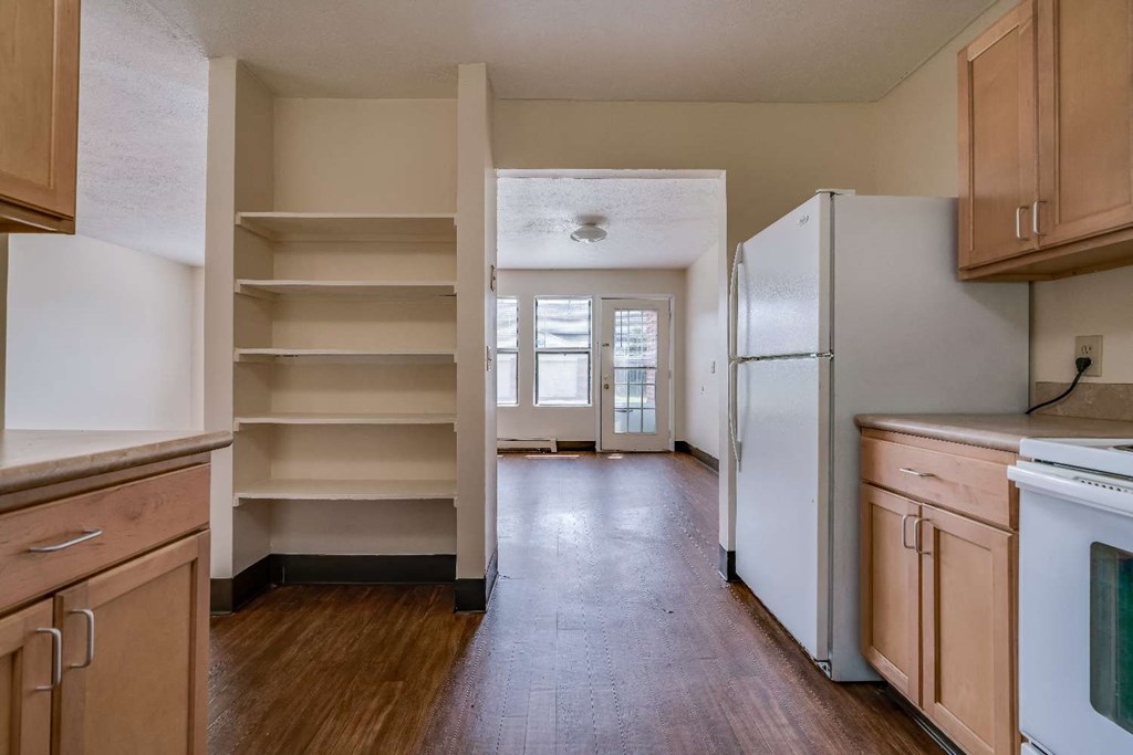 an empty kitchen with wooden floors and a refrigerator