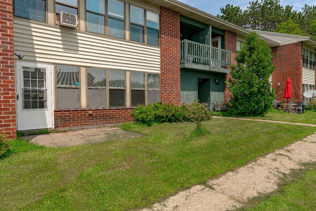 the front yard of an apartment building with grass and a sidewalk