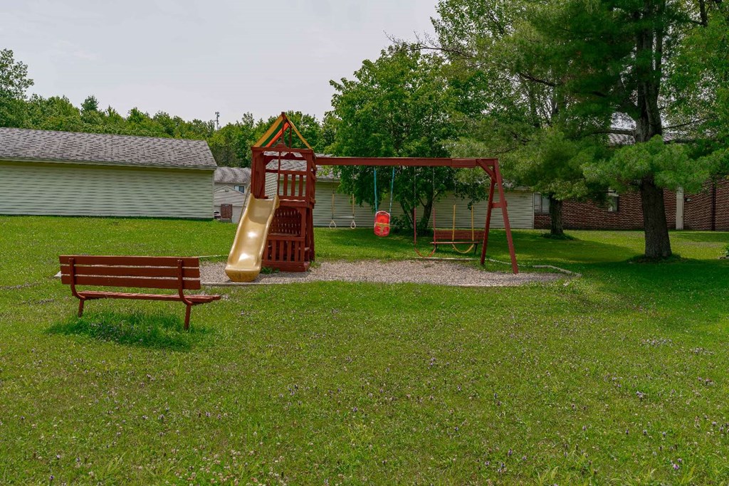 a playground with a swing set and a bench in a yard