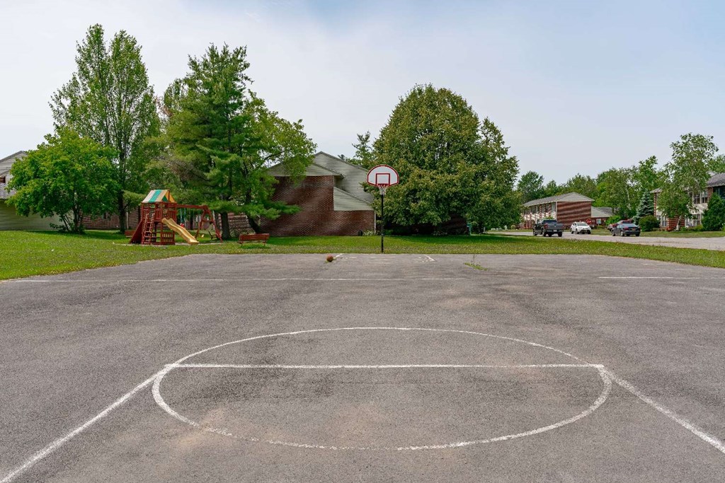 a basketball court in a park with a house in the background