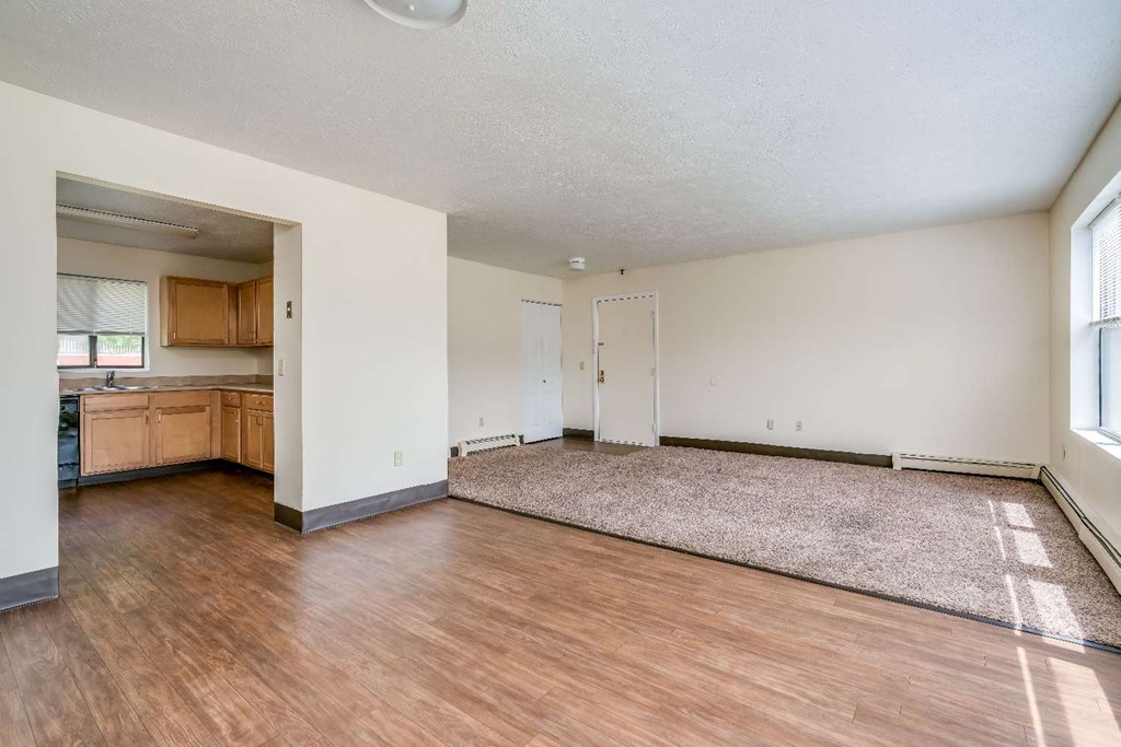 an empty living room and kitchen with wood flooring