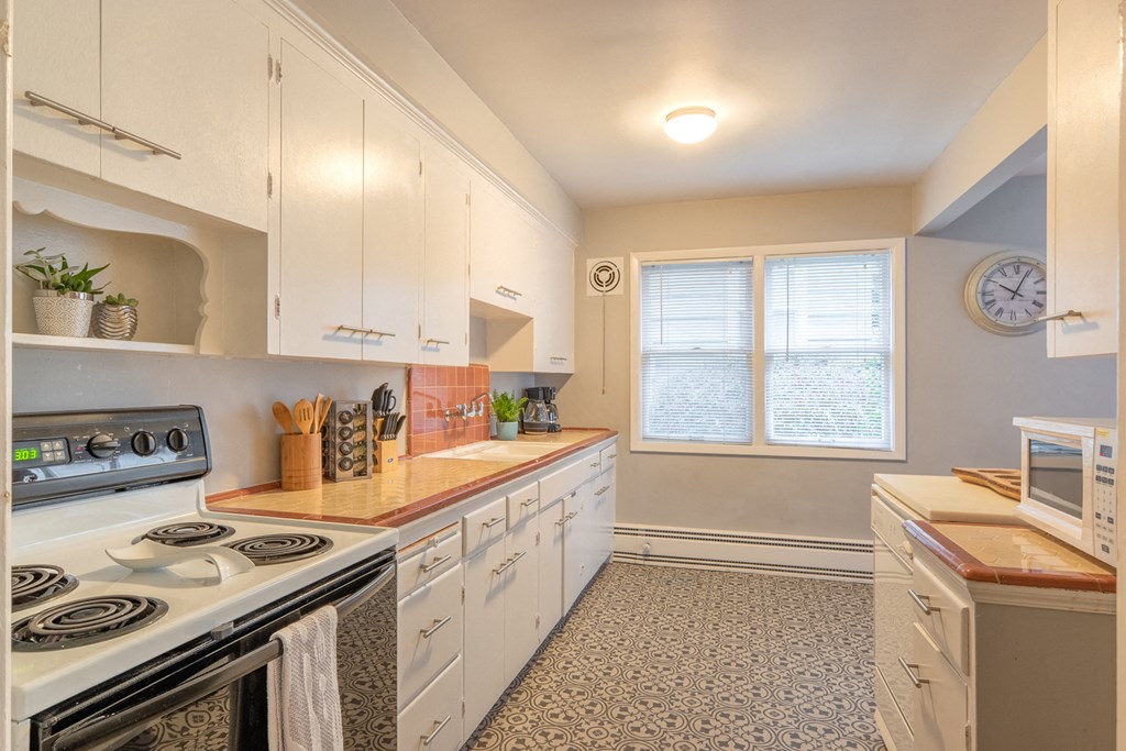 a kitchen with white cabinets and appliances and a window
