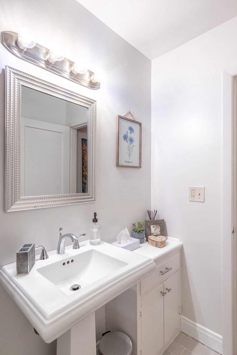 a white bathroom with a white sink and a mirror