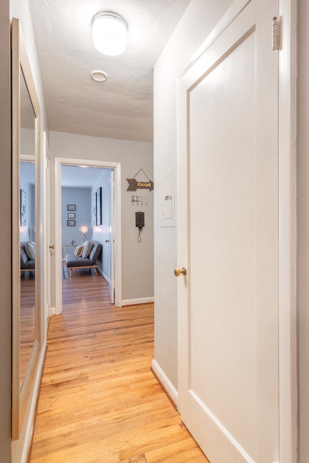 the hallway of a home with white walls and a wooden floor