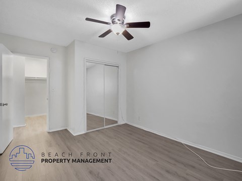 A room with a ceiling fan and a logo for Beach Front Property Management.